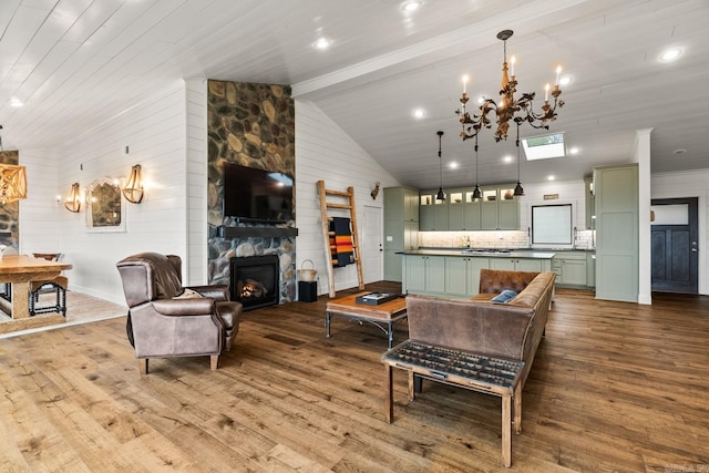 living room with beam ceiling, high vaulted ceiling, a chandelier, wood-type flooring, and a fireplace