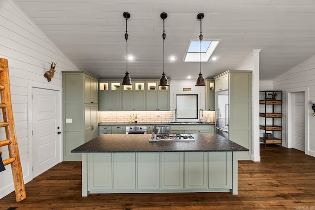 kitchen featuring appliances with stainless steel finishes, dark hardwood / wood-style flooring, a center island, and hanging light fixtures