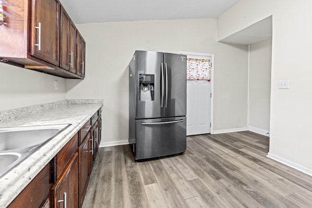 kitchen with dark brown cabinets, light hardwood / wood-style flooring, stainless steel refrigerator with ice dispenser, and sink