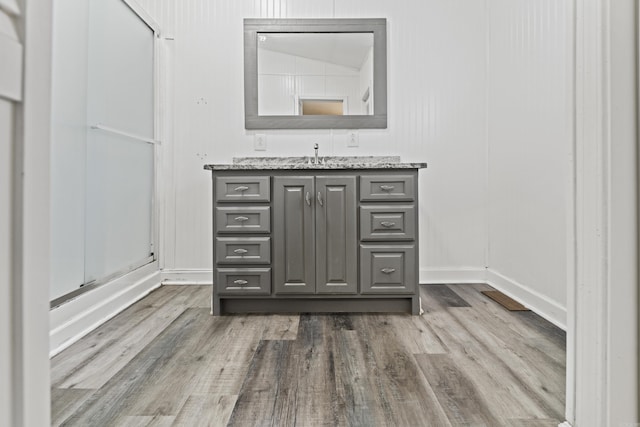 bathroom with wood-type flooring, vanity, and lofted ceiling