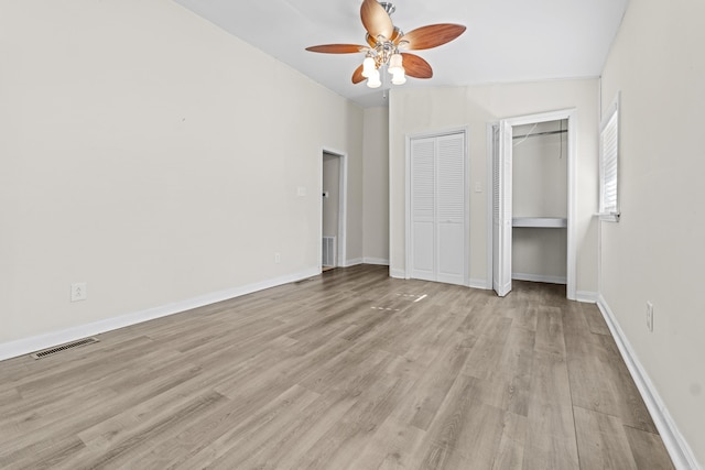 unfurnished bedroom with ceiling fan, vaulted ceiling, multiple closets, and light hardwood / wood-style flooring