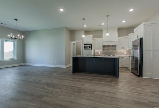 kitchen featuring a center island with sink, sink, appliances with stainless steel finishes, white cabinetry, and wood-type flooring