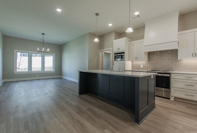 kitchen with stainless steel appliances, a kitchen island, light hardwood / wood-style flooring, premium range hood, and white cabinets