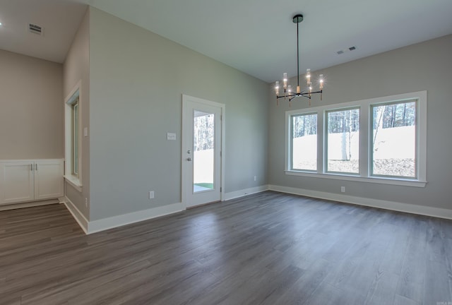 empty room featuring an inviting chandelier and dark wood-type flooring