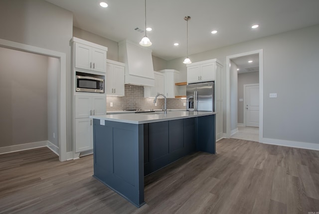 kitchen with wood-type flooring, white cabinets, hanging light fixtures, and appliances with stainless steel finishes