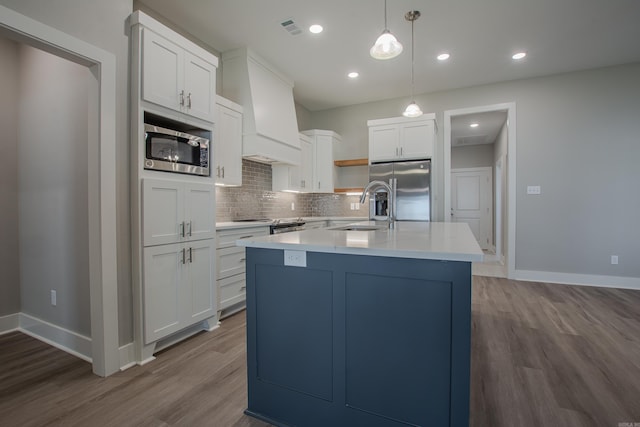 kitchen with hardwood / wood-style floors, sink, appliances with stainless steel finishes, decorative light fixtures, and white cabinetry