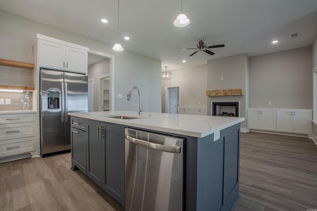 kitchen featuring appliances with stainless steel finishes, a kitchen island with sink, sink, pendant lighting, and white cabinetry