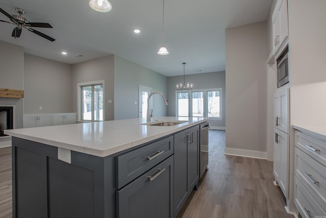 kitchen with a wealth of natural light, sink, white cabinets, and a center island with sink