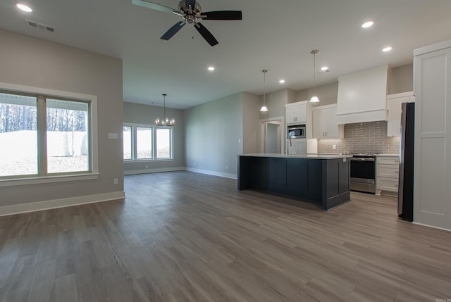 kitchen with white cabinetry, appliances with stainless steel finishes, hardwood / wood-style floors, a kitchen island, and custom exhaust hood