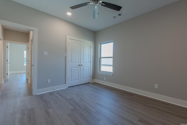 unfurnished bedroom featuring wood-type flooring, a closet, and ceiling fan