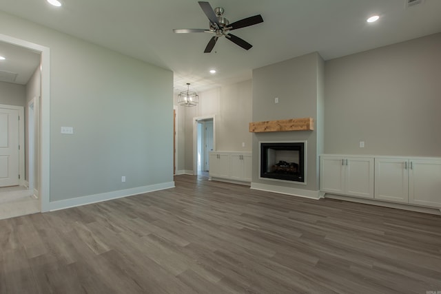 unfurnished living room featuring light hardwood / wood-style floors and ceiling fan with notable chandelier