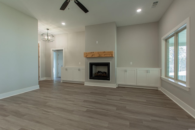 unfurnished living room featuring hardwood / wood-style floors and ceiling fan with notable chandelier