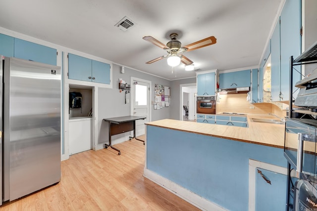 kitchen featuring blue cabinetry, light hardwood / wood-style floors, decorative backsplash, appliances with stainless steel finishes, and ornamental molding
