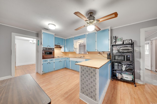 kitchen featuring kitchen peninsula, light hardwood / wood-style flooring, black oven, and blue cabinets