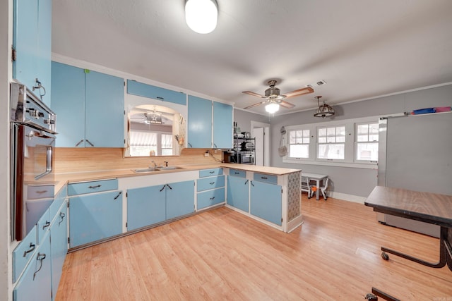 kitchen featuring light wood-type flooring, blue cabinets, ceiling fan, sink, and oven