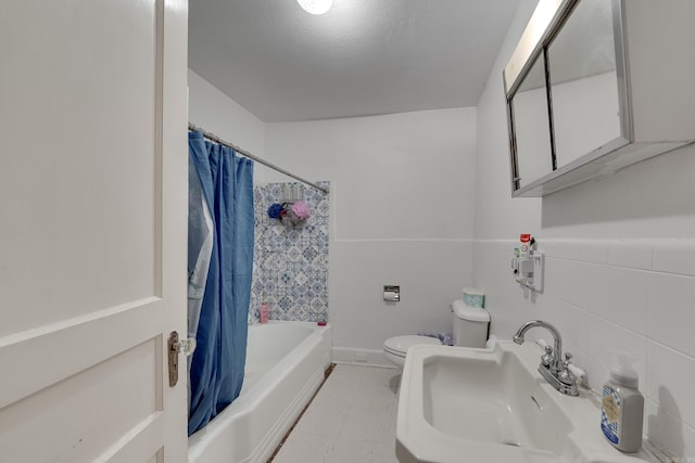 full bathroom with sink, shower / bath combo, toilet, and tile walls