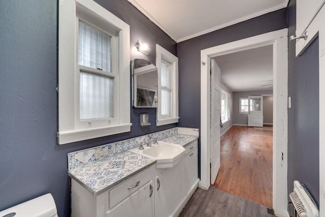 bathroom featuring crown molding, vanity, wood-type flooring, and toilet