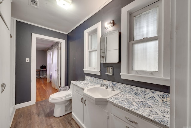 bathroom with crown molding, vanity, wood-type flooring, and toilet