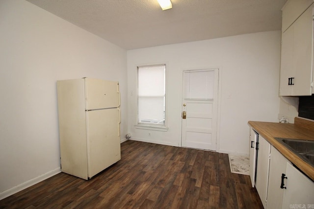 kitchen with white cabinetry, sink, dark wood-type flooring, white fridge, and a textured ceiling