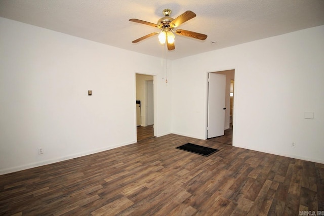 empty room with ceiling fan, dark wood-type flooring, and a textured ceiling