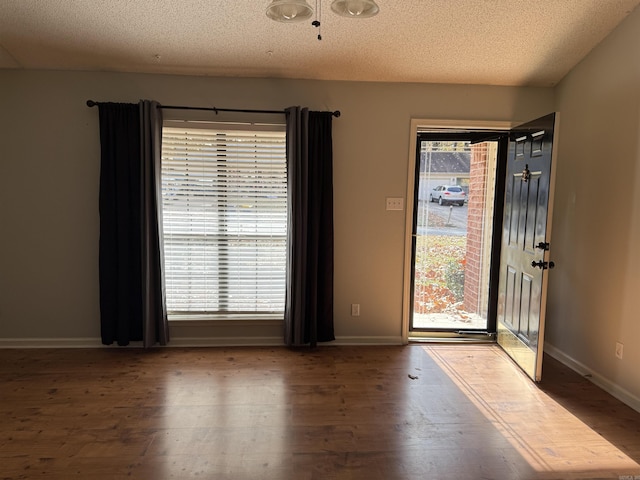 unfurnished room with hardwood / wood-style floors and a textured ceiling