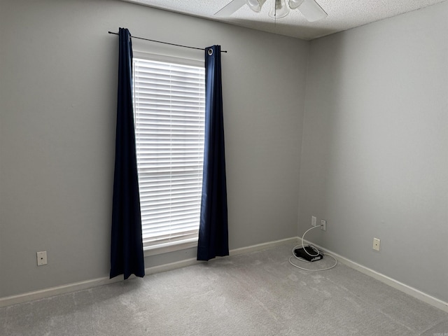 carpeted spare room featuring a textured ceiling and ceiling fan