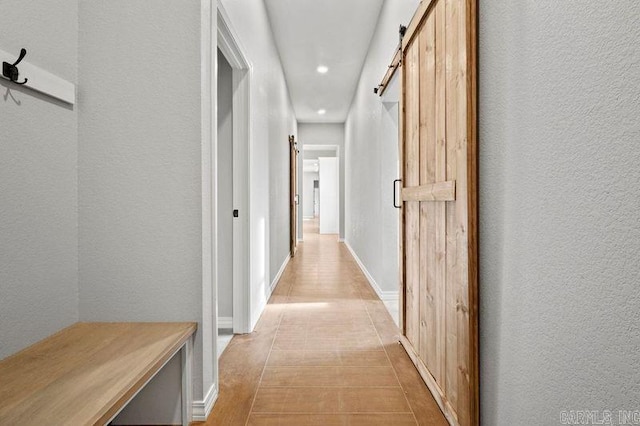 hall with a barn door and light tile patterned flooring