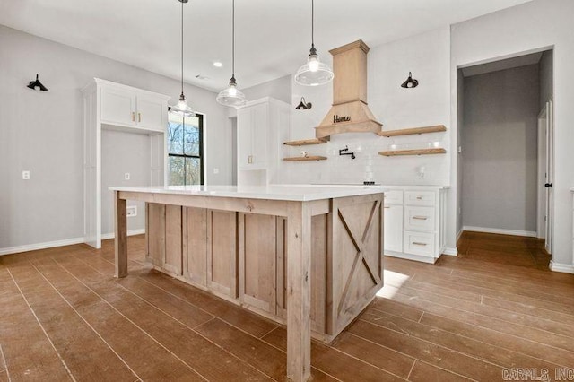 kitchen with a kitchen island, dark hardwood / wood-style flooring, white cabinetry, and custom range hood