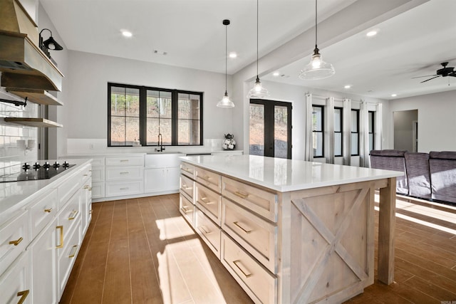 kitchen featuring black electric stovetop, decorative light fixtures, white cabinets, dark hardwood / wood-style floors, and a kitchen island