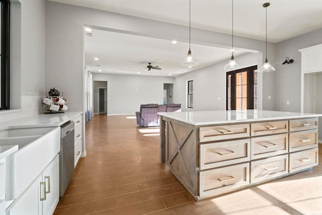 kitchen featuring stainless steel dishwasher, ceiling fan, hardwood / wood-style flooring, a kitchen island, and hanging light fixtures