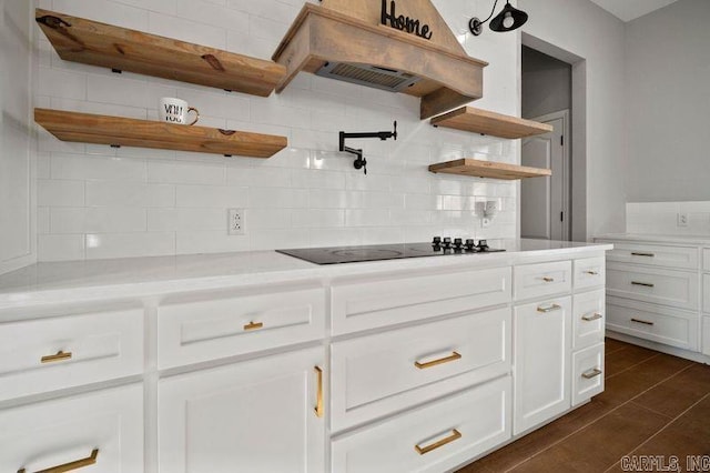 kitchen with white cabinetry, backsplash, black electric cooktop, custom range hood, and dark tile patterned flooring