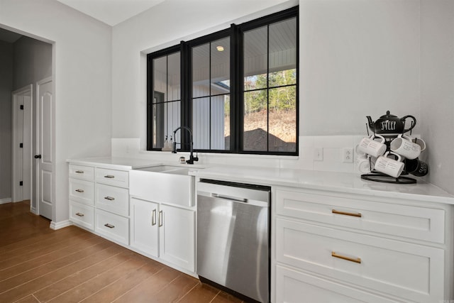 kitchen featuring white cabinetry, sink, light stone counters, light hardwood / wood-style flooring, and stainless steel dishwasher