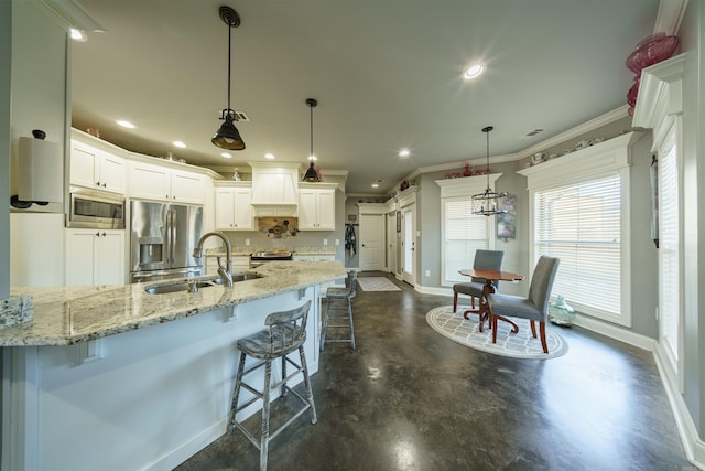 kitchen with sink, pendant lighting, a breakfast bar, white cabinets, and appliances with stainless steel finishes