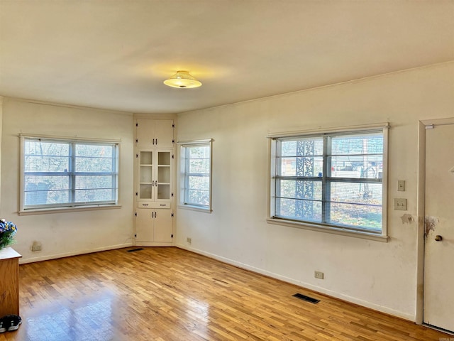 spare room featuring light wood-type flooring and crown molding