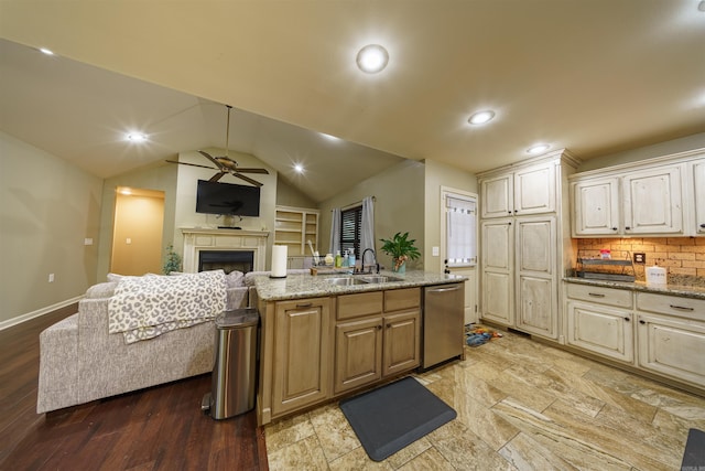 kitchen with sink, vaulted ceiling, stainless steel dishwasher, light wood-type flooring, and light stone counters