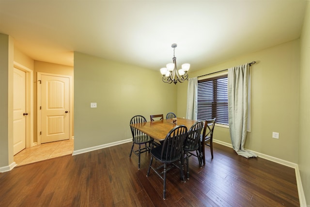 dining area with dark hardwood / wood-style flooring and an inviting chandelier