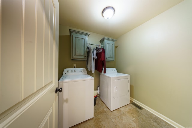 clothes washing area with separate washer and dryer and cabinets