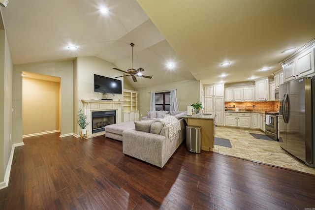 living room featuring ceiling fan, sink, lofted ceiling, and dark wood-type flooring