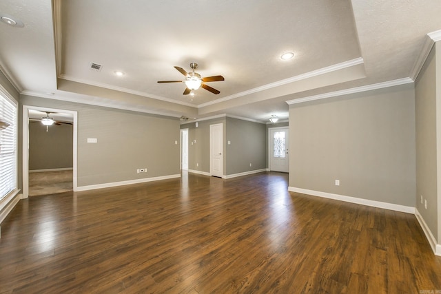 empty room with a tray ceiling, crown molding, and dark hardwood / wood-style flooring