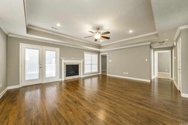 unfurnished living room featuring a raised ceiling, crown molding, ceiling fan, and dark wood-type flooring