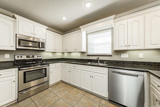 kitchen with a textured ceiling, stainless steel appliances, sink, light tile patterned floors, and white cabinets