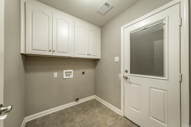 washroom with hookup for an electric dryer, washer hookup, cabinets, a textured ceiling, and light tile patterned floors