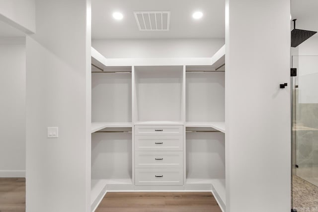 walk in closet with light hardwood / wood-style flooring