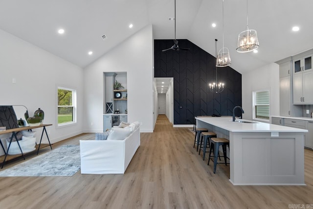 kitchen featuring pendant lighting, white cabinets, a center island with sink, sink, and light hardwood / wood-style floors