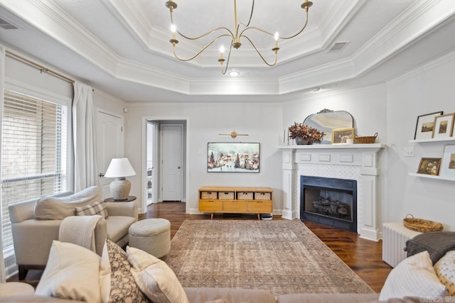 living room with a raised ceiling, crown molding, a chandelier, and dark hardwood / wood-style floors