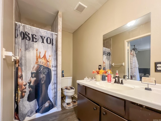 bathroom with vanity, hardwood / wood-style flooring, ceiling fan, toilet, and walk in shower