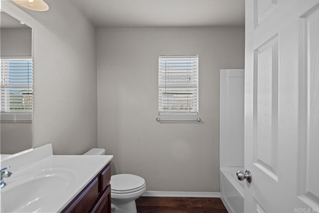 bathroom with a tub, hardwood / wood-style flooring, vanity, and toilet