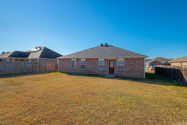 rear view of property featuring a fenced backyard, brick siding, and a lawn