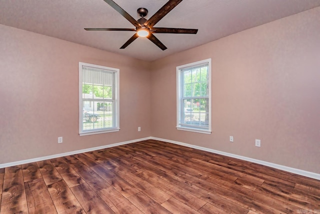 spare room with a textured ceiling, a wealth of natural light, dark wood-type flooring, and ceiling fan