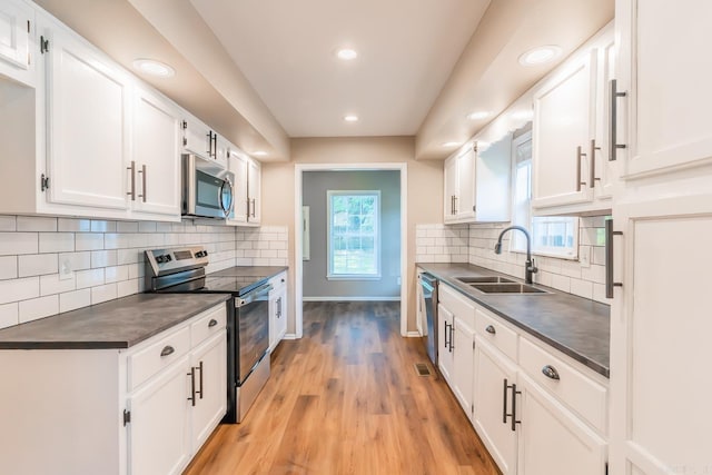 kitchen featuring light wood-type flooring, tasteful backsplash, stainless steel appliances, sink, and white cabinets